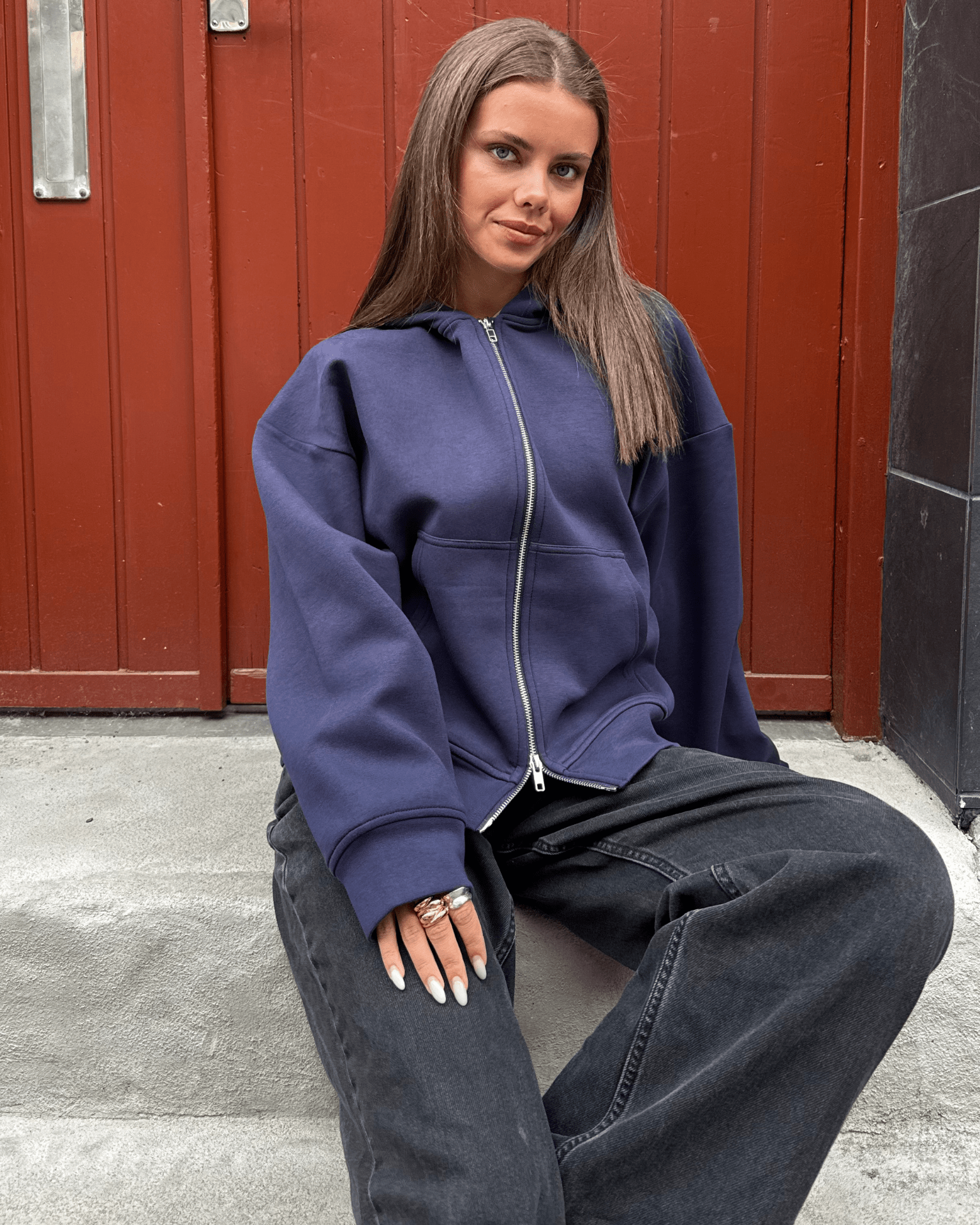 Navyblå Ash Scuba zip hoodie i boxfit på model, der sidder foran en rød dør.