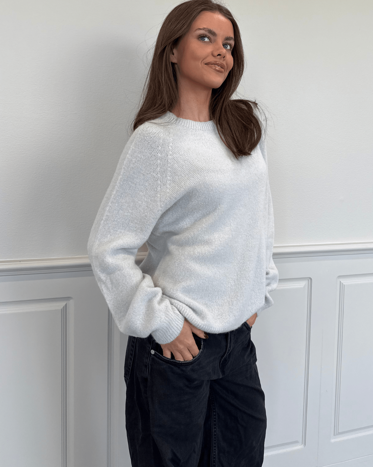 Model i lysegrå Molli striktrøje og mørke jeans