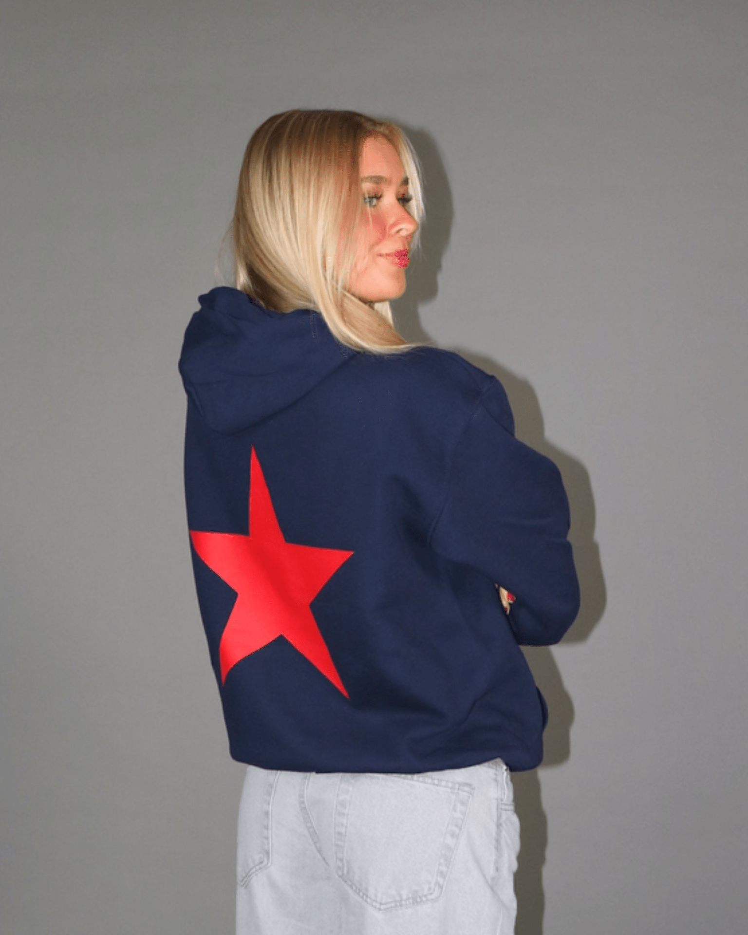 Navyblå hoodie med stort rødt stjerneprint på ryggen, vist bagfra på model