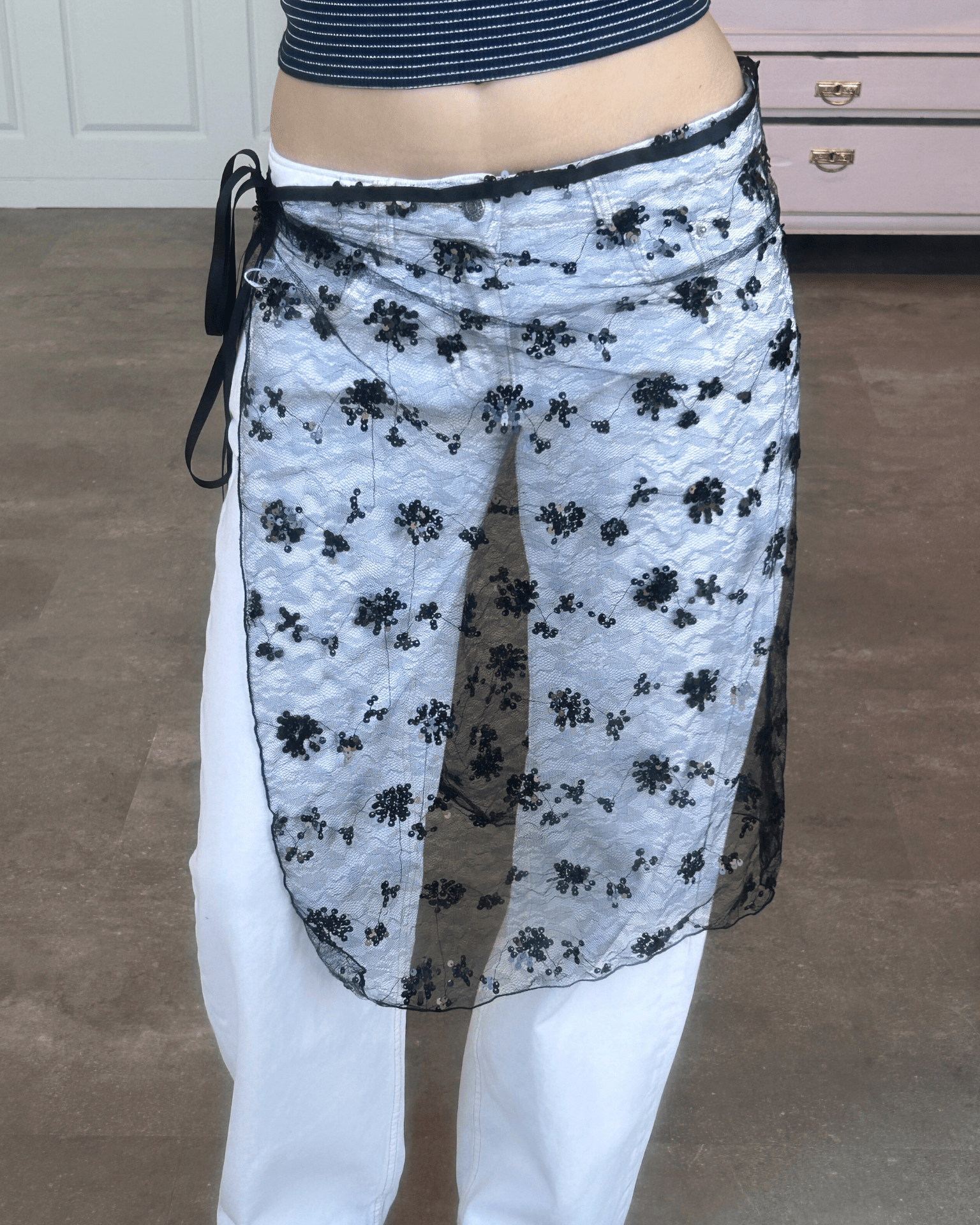 Sort, gennemsigtig blondesarong med palietter stylet over hvide bukser