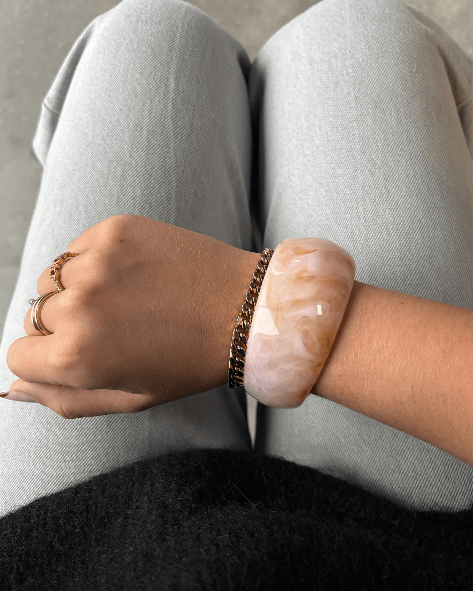 Chunky armbånd i meleret pink og sandfarvet akryl på et håndled