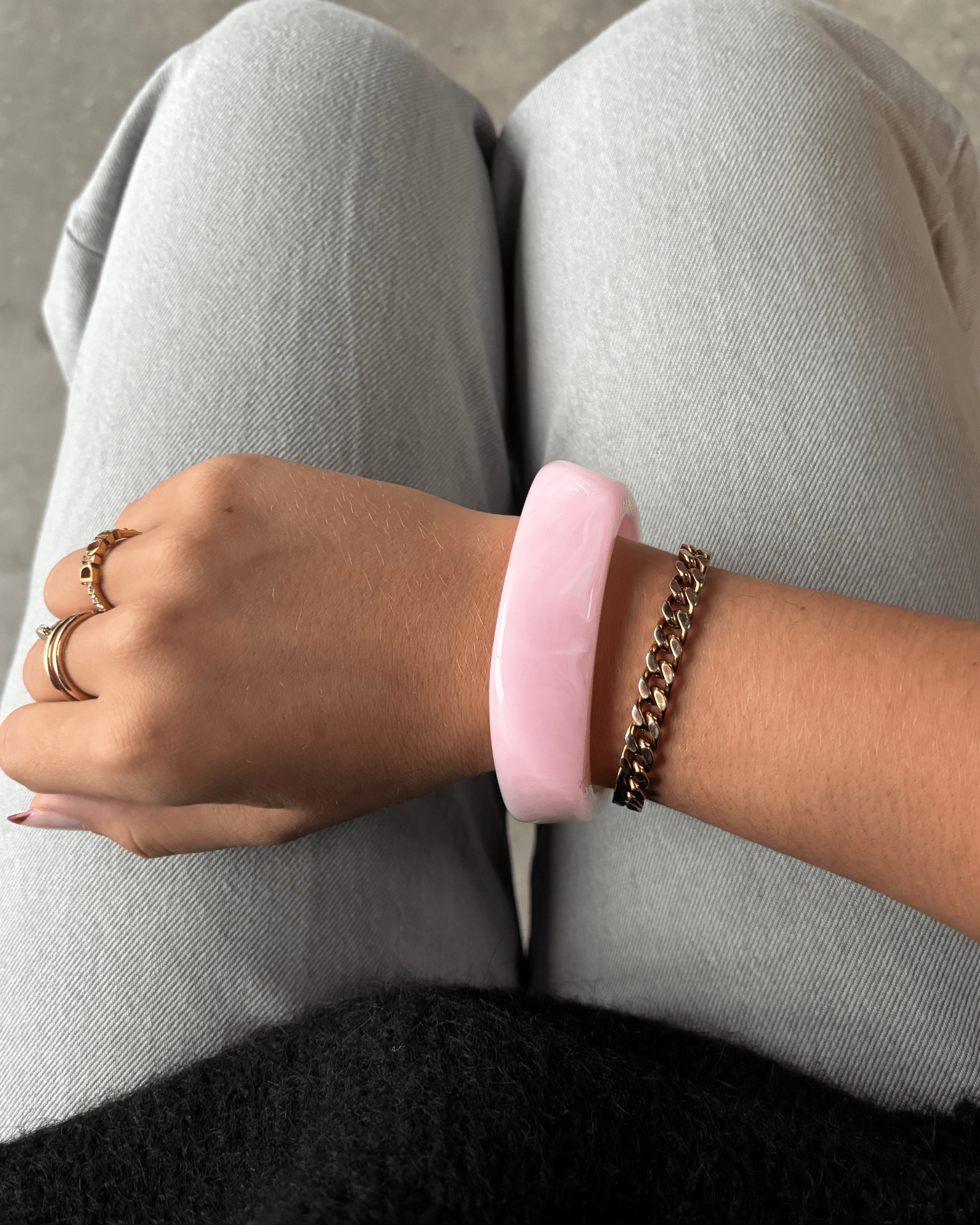 Chunky lyserødt armbånd i akryl på håndleddet sammen med en guldkæde