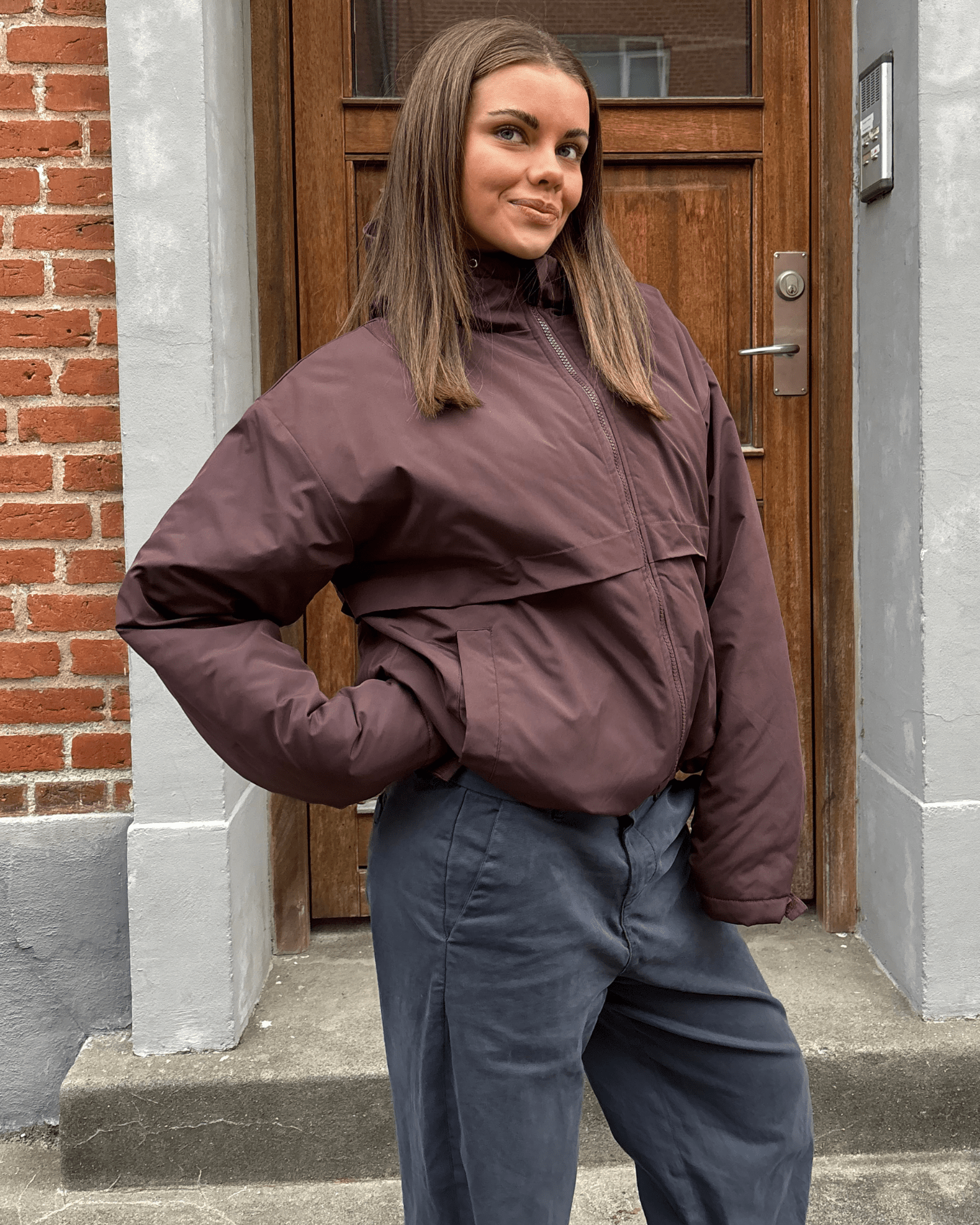 Brun Juno dynejakke med hætte og lynlås, vist på model