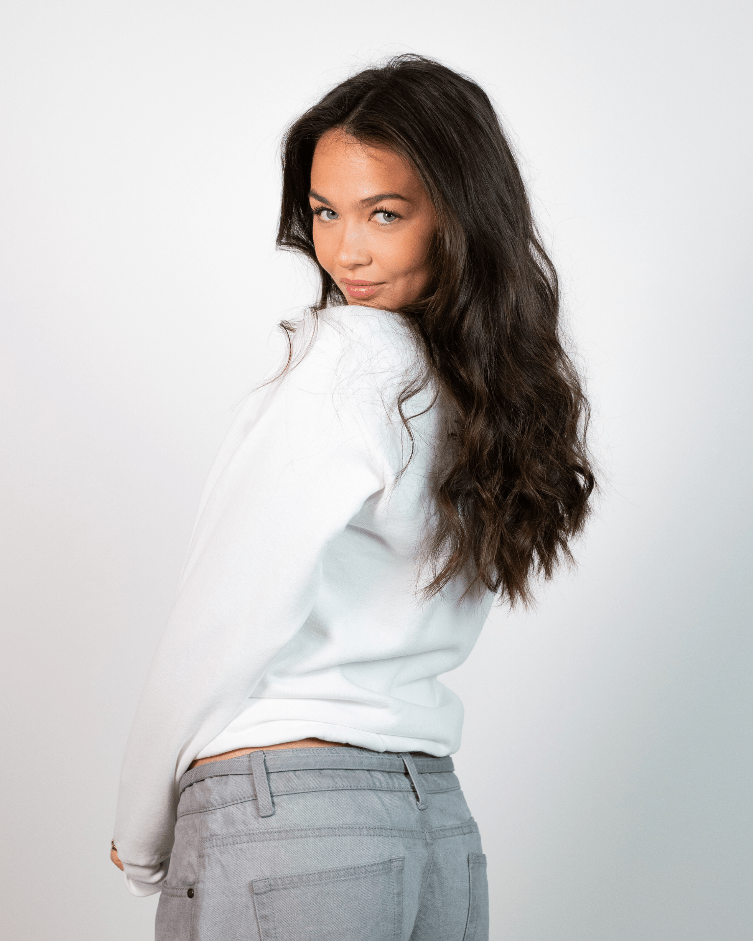 Kvinde i hvid Fruit sweatshirt og grå jeans set bagfra