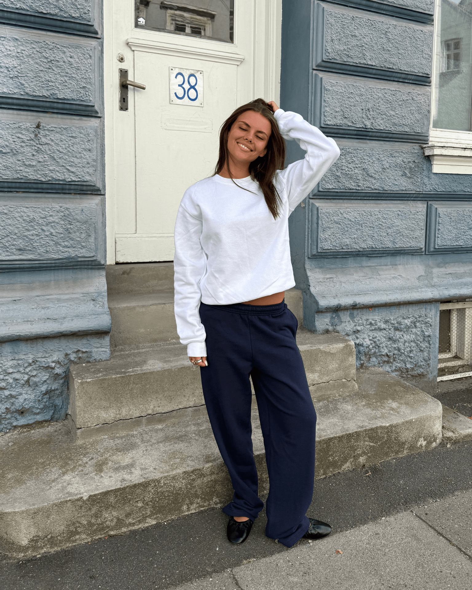 Hvid Fruit sweatshirt i bomuldsblanding på model foran en blå bygning