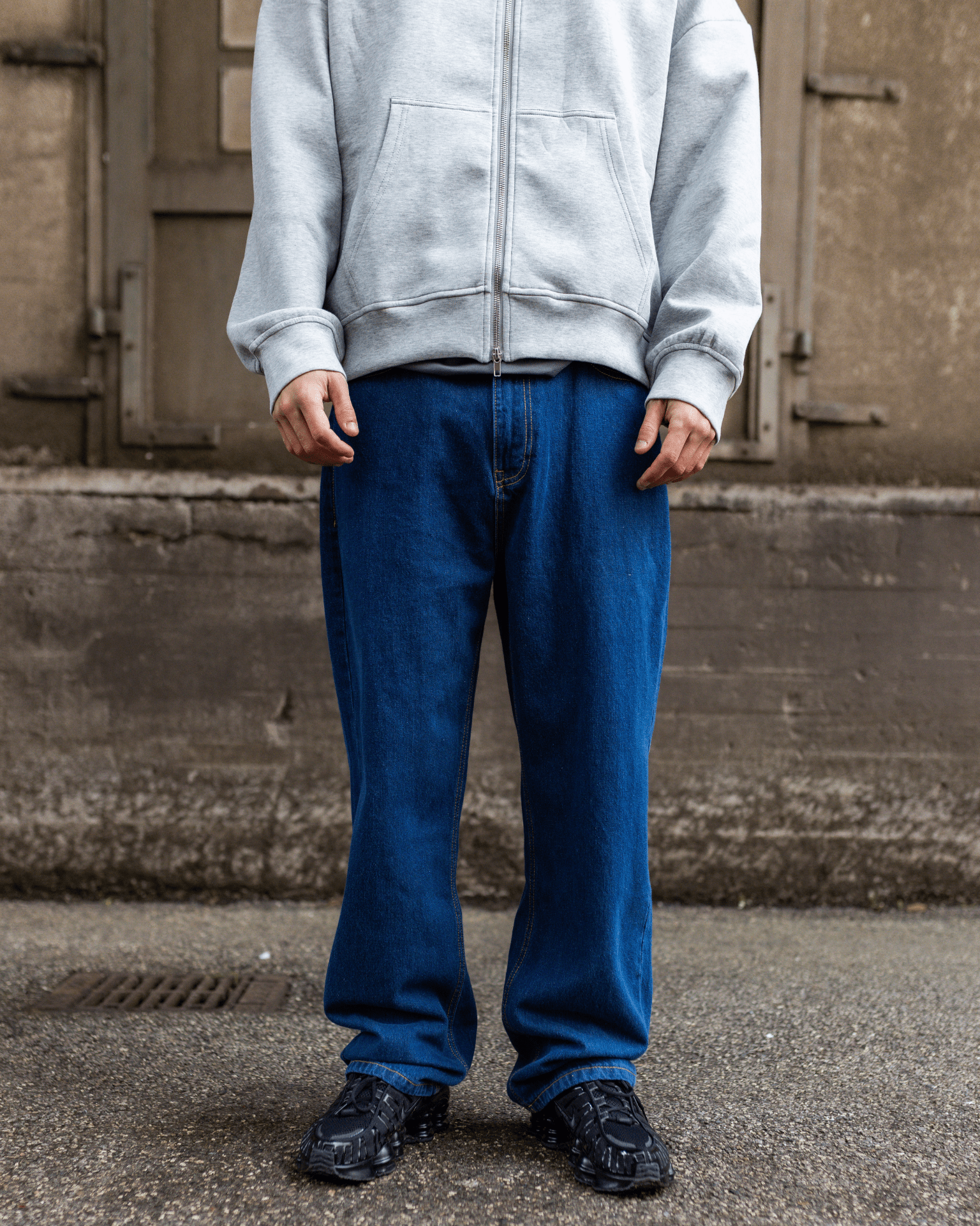 Mørkeblå Tyler baggy jeans i bomuld med lav talje, vist på model med grå hættetrøje.