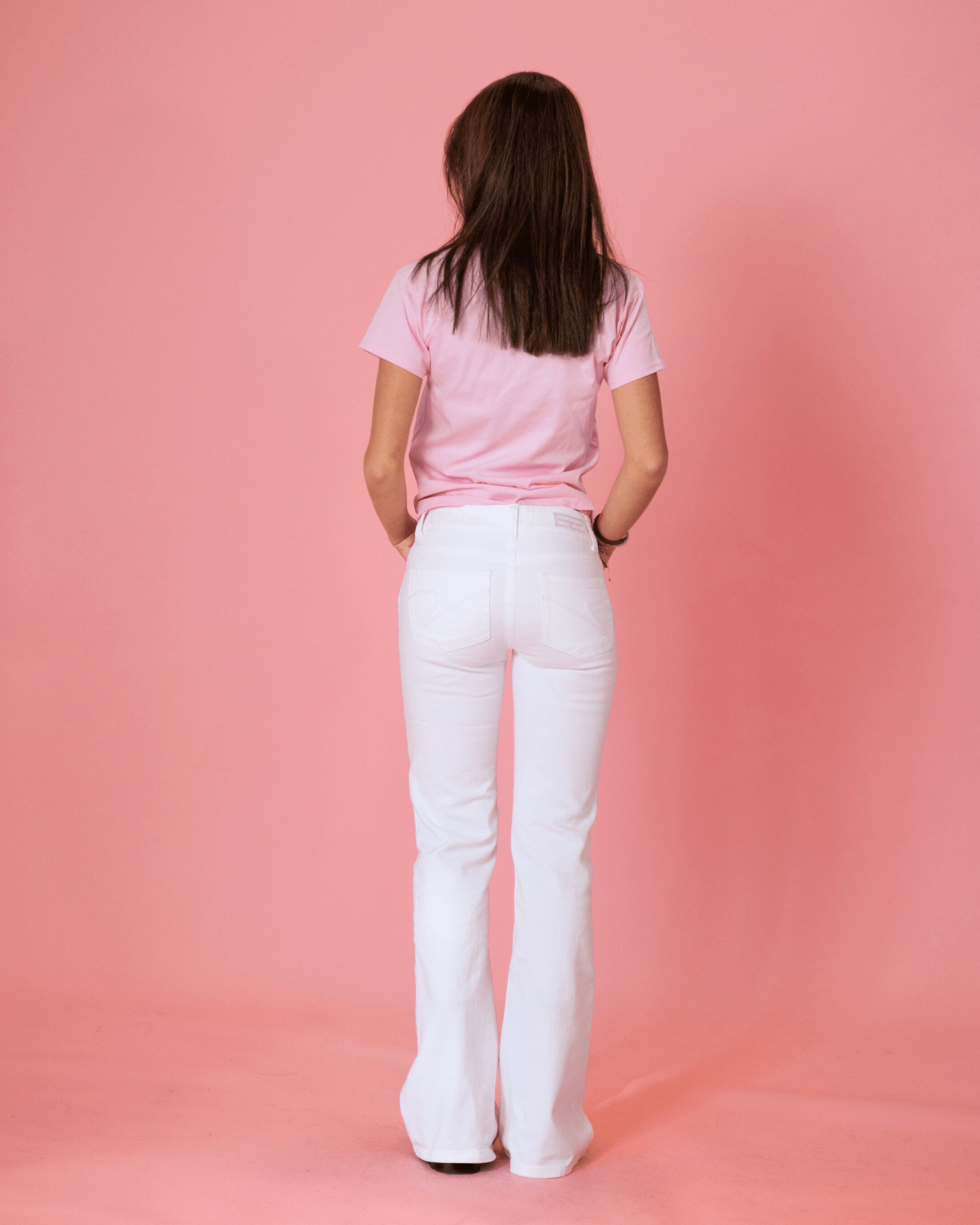 Hvide Erika low waist bootcut jeans set bagfra på en model mod lyserød baggrund