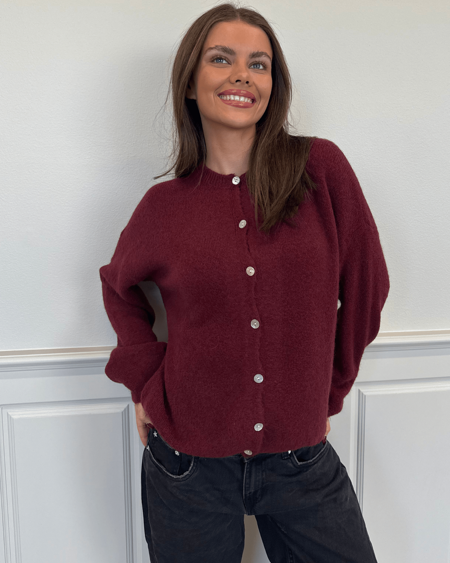 Vinrød strikket Molli cardigan med knapper på en smilende model