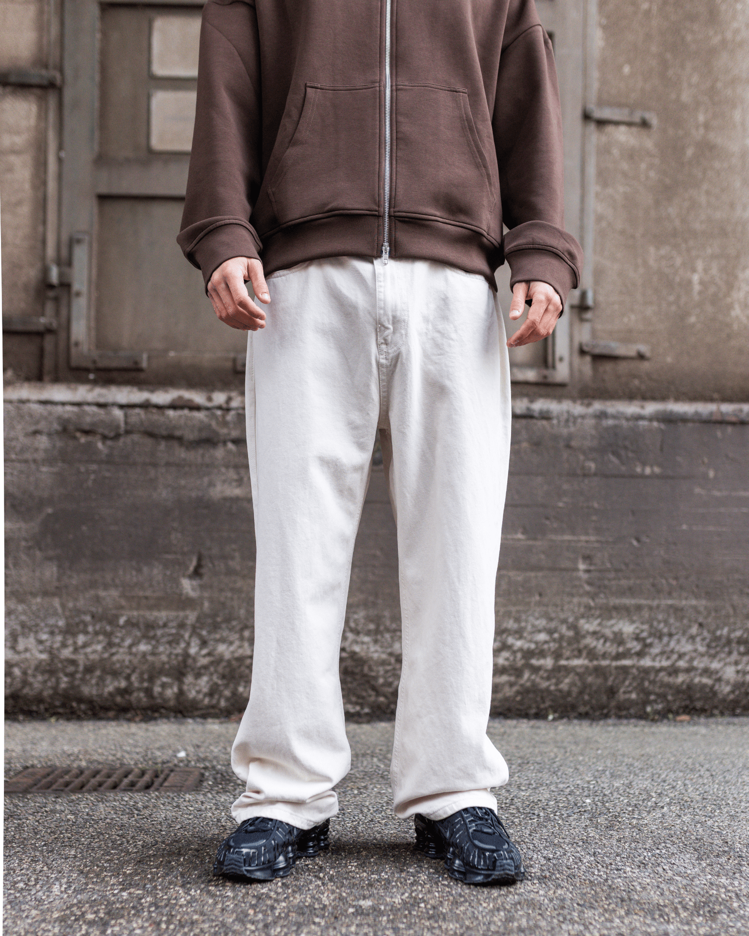 Model i off white Tyler baggy jeans med lav talje og brun hættetrøje