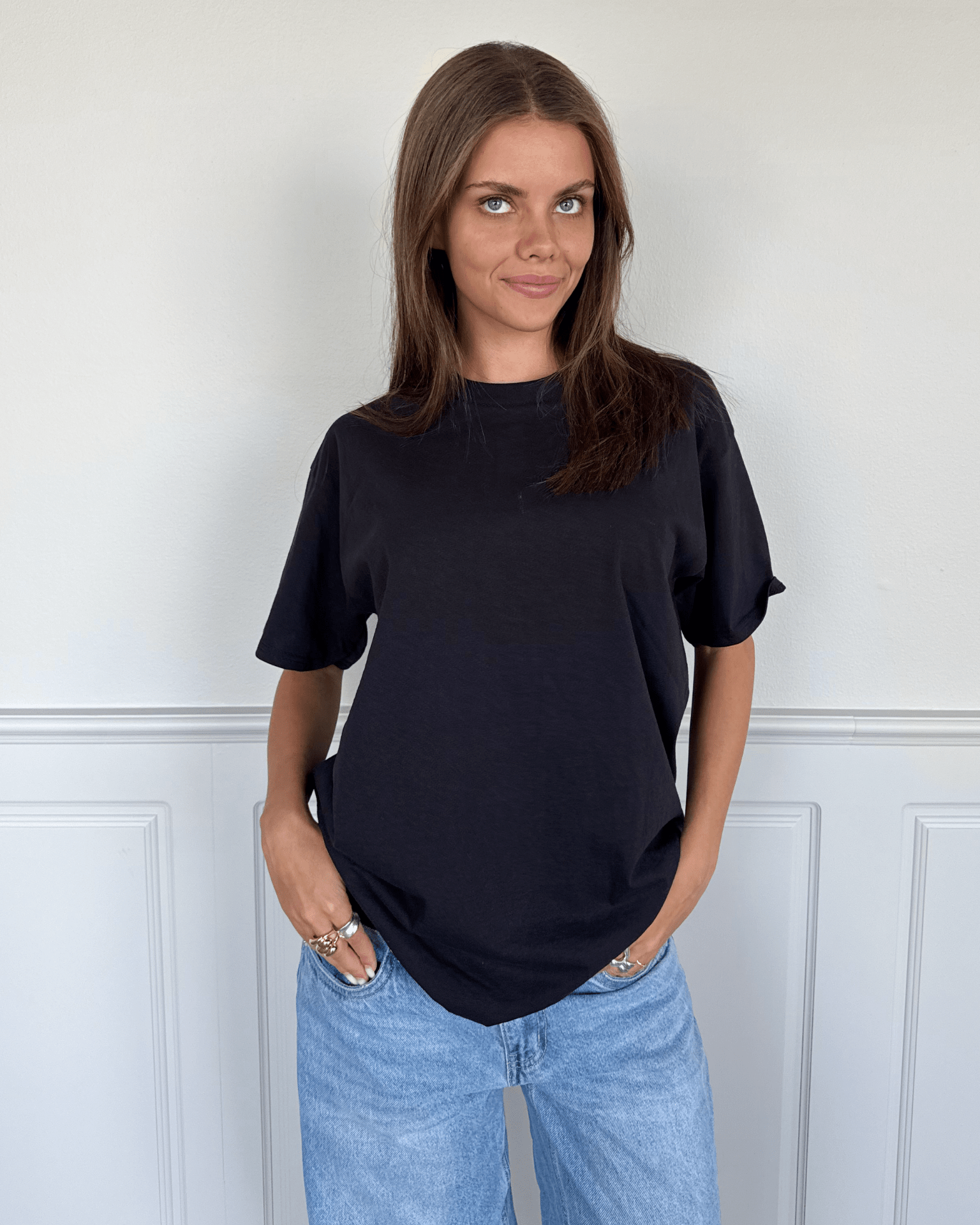 Kvinde i sort Fruit of the Loom t-shirt i bomuld og blå jeans