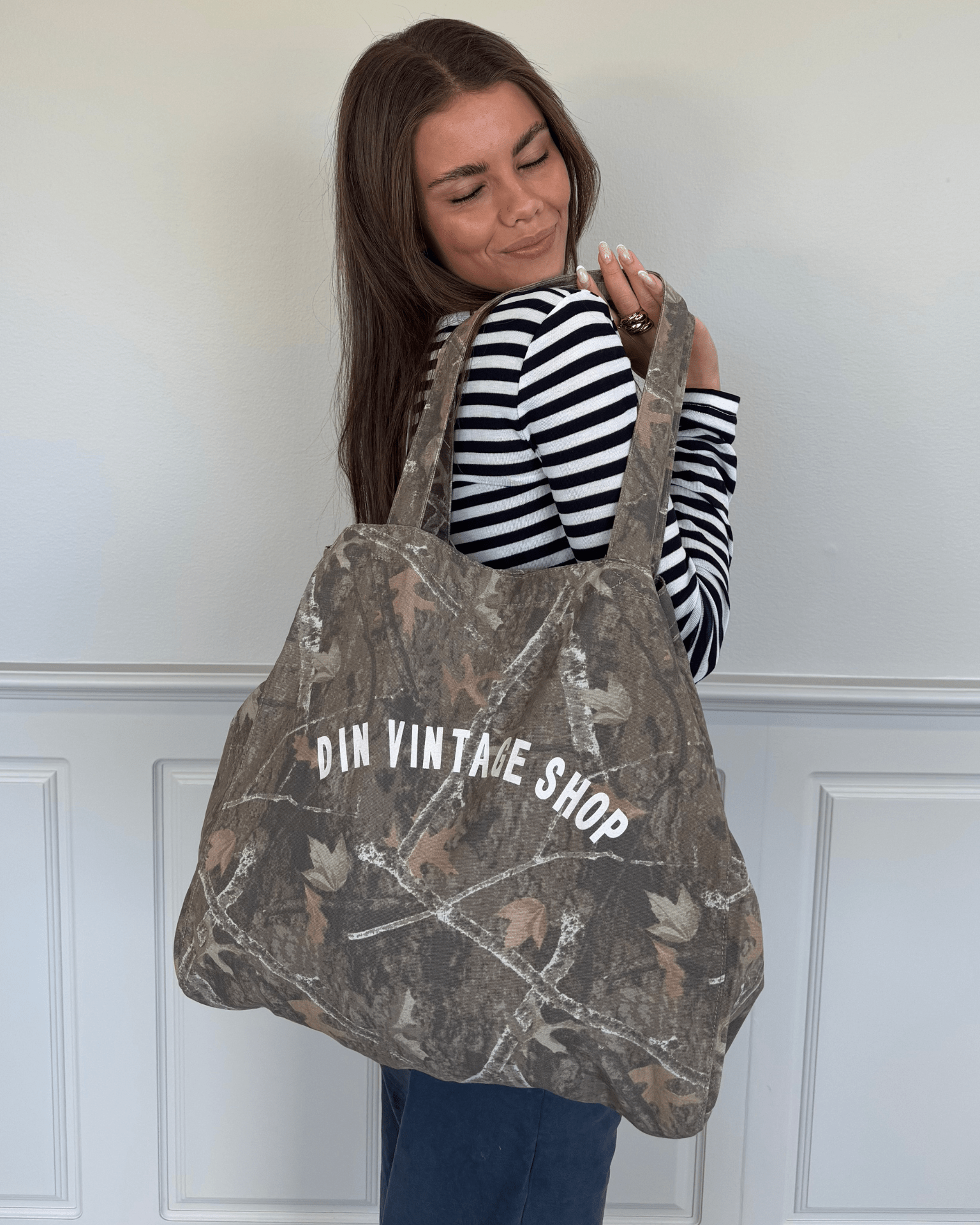 Grøn camouflage-totebag i stof med hvidt Din Vintage Shop-logo over skulderen.