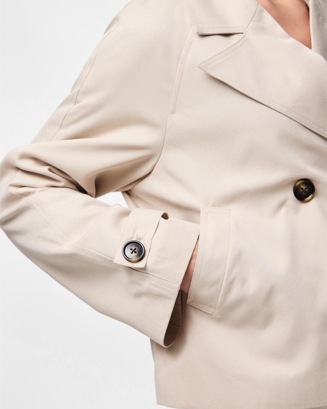 Nærbillede af lysegrå Scarlett kort trenchcoat med knapper og sidelomme