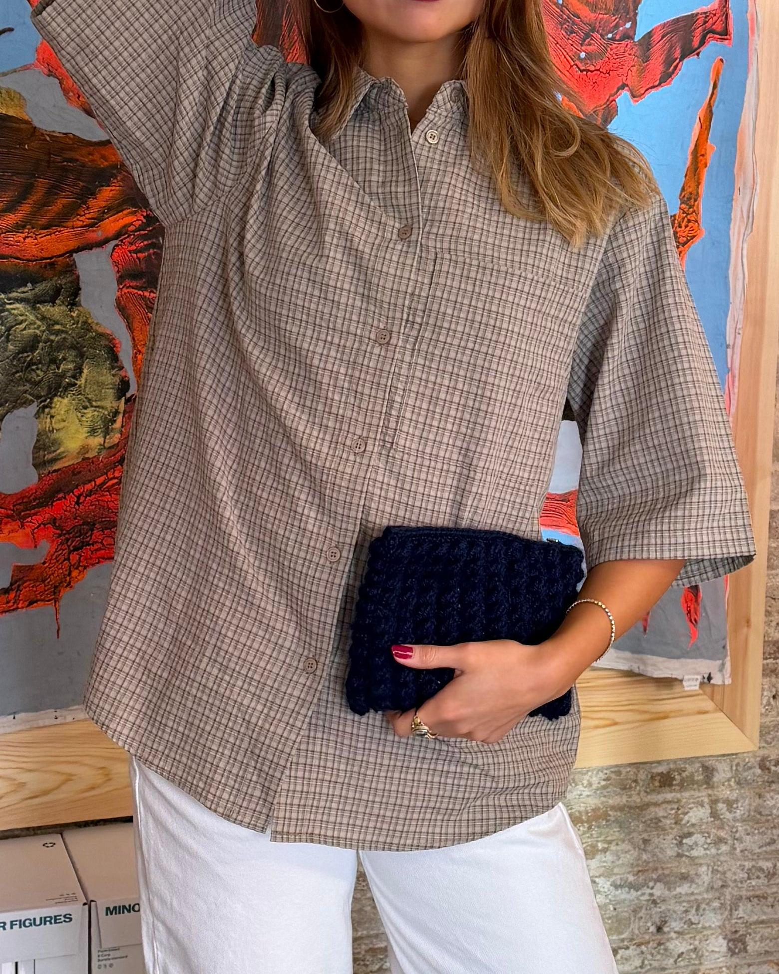 Håndhæklet navyblå clutch i mønstret design holdt af kvinde i ternet skjorte