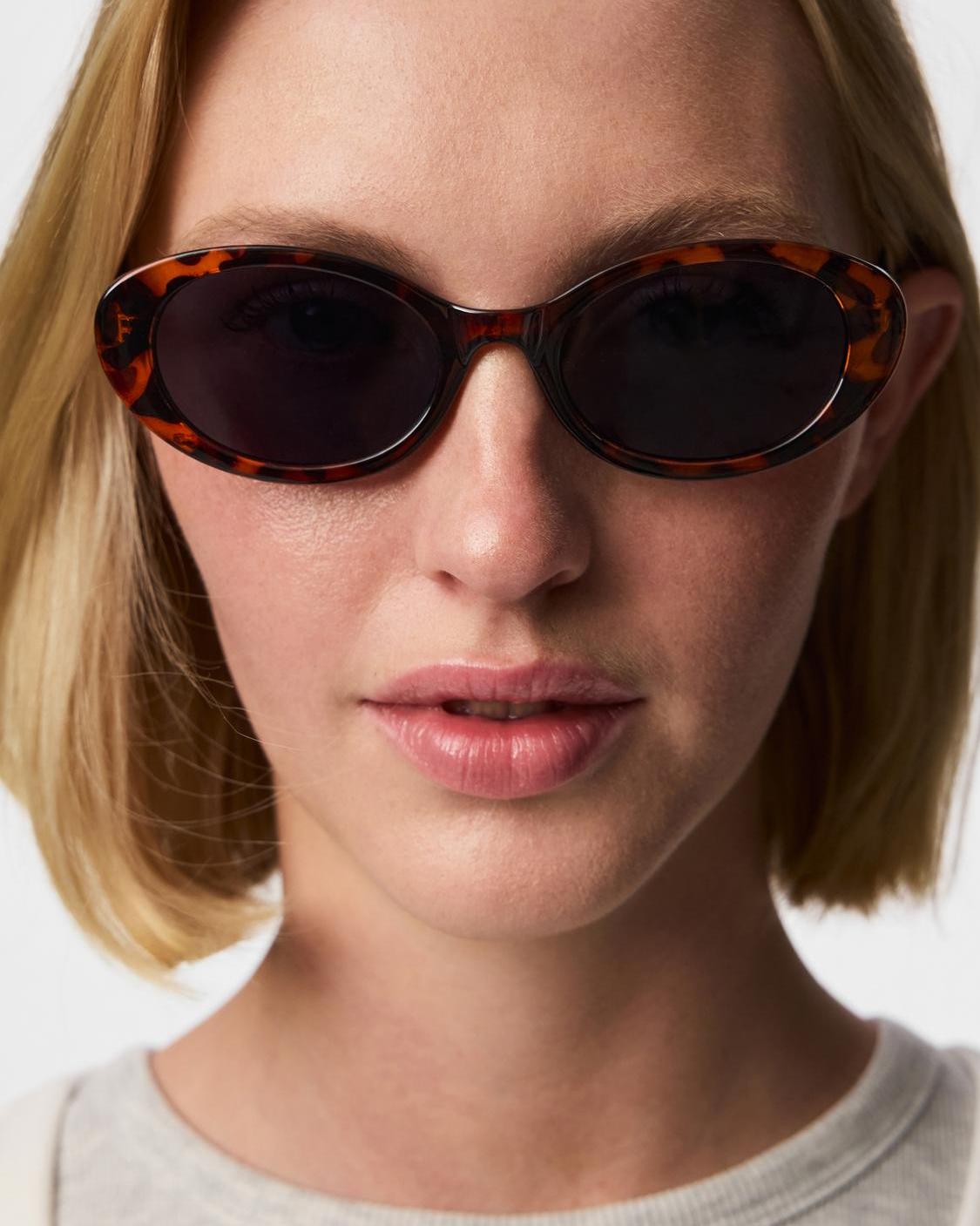 Sanna solbriller fra PIECES med brun skildpaddemønstret ramme og mørke glas på en model.
