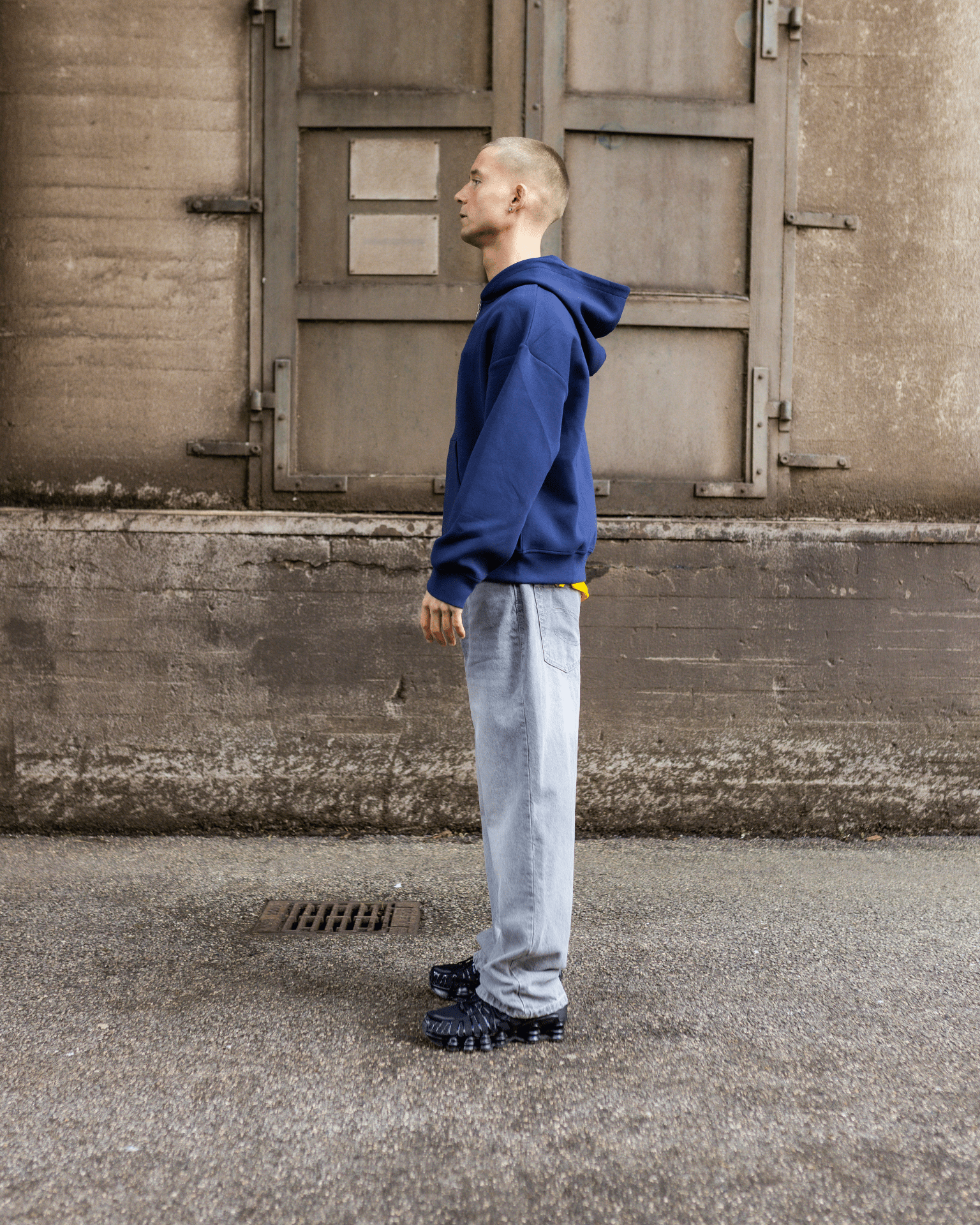 Model i profil med lysegrå Tyler baggy jeans og blå hættetrøje