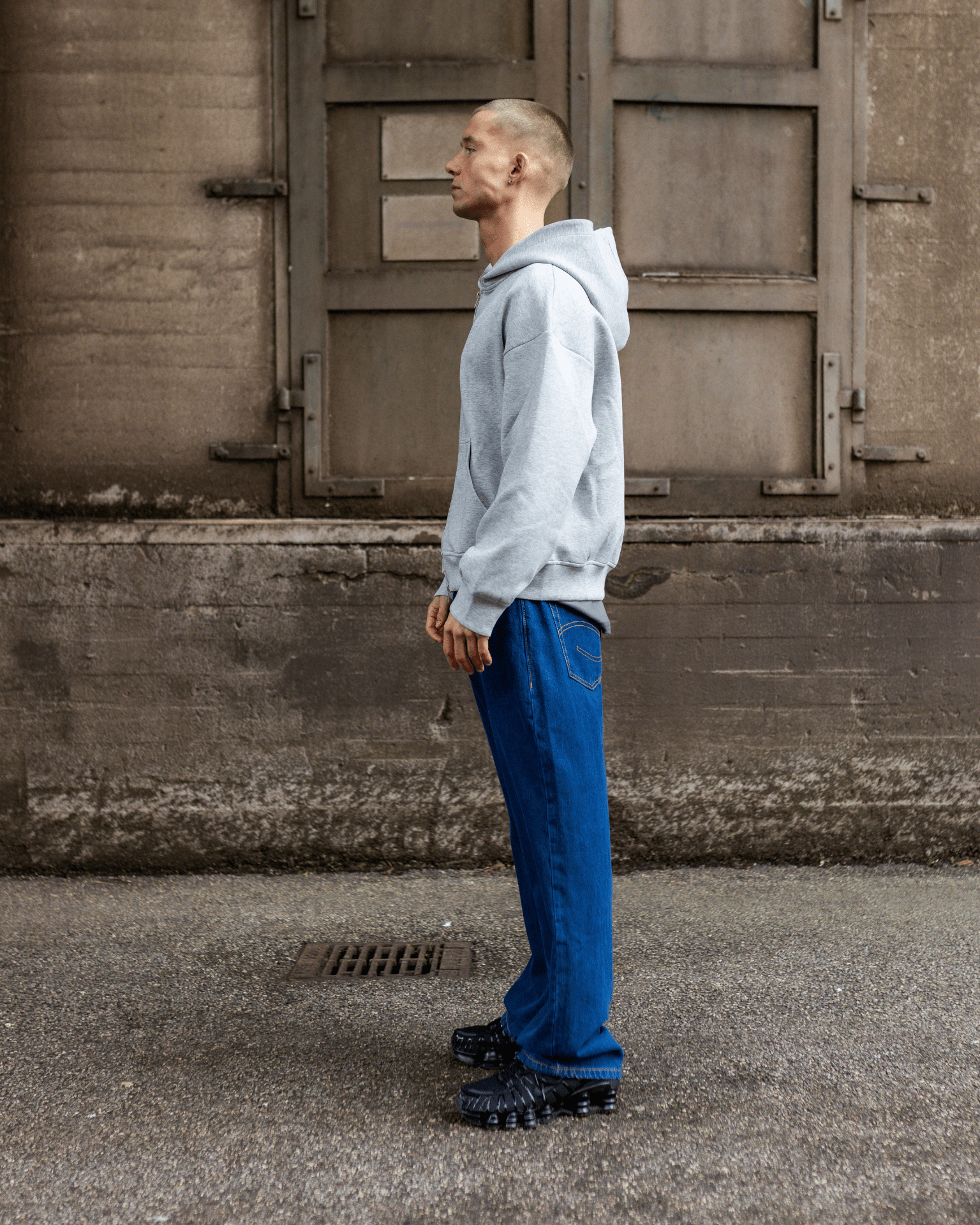 Model i mørkeblå Tyler baggy jeans og grå hættetrøje set fra siden