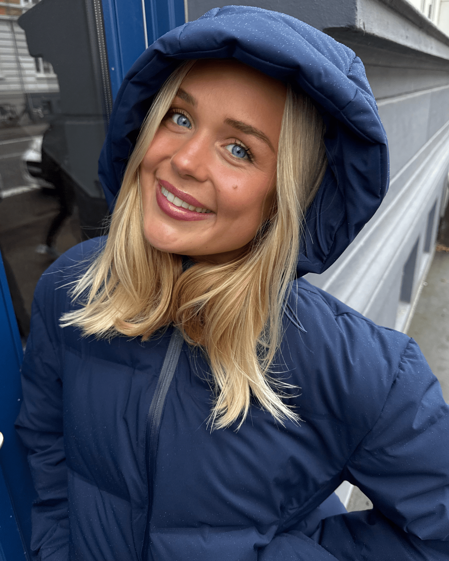 Smilende kvinde i navyblå Isa dunjakke med stor hætte