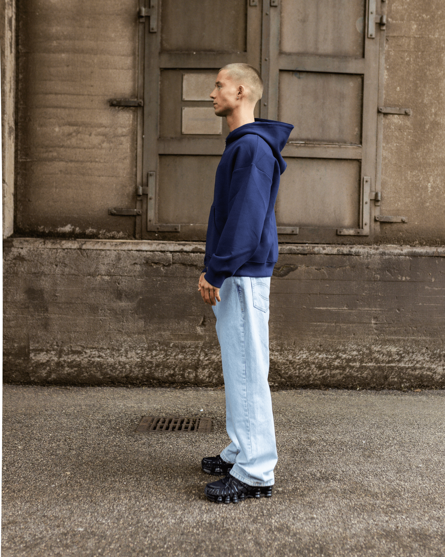 Model i profil med lyseblå Tyler baggy jeans og mørkeblå hættetrøje