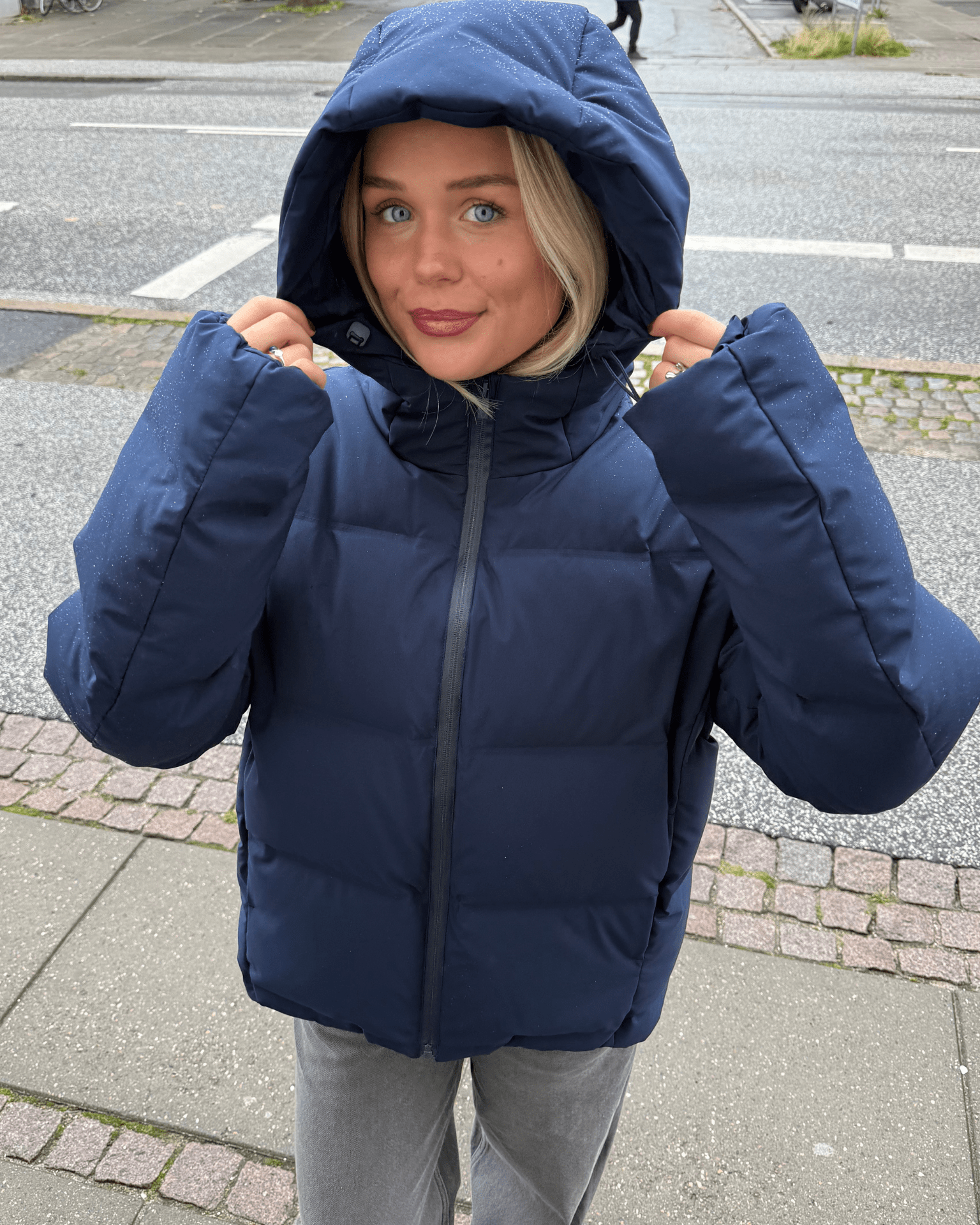 Navyblå Isa dunjakke med stor hætte og lynlås på en model