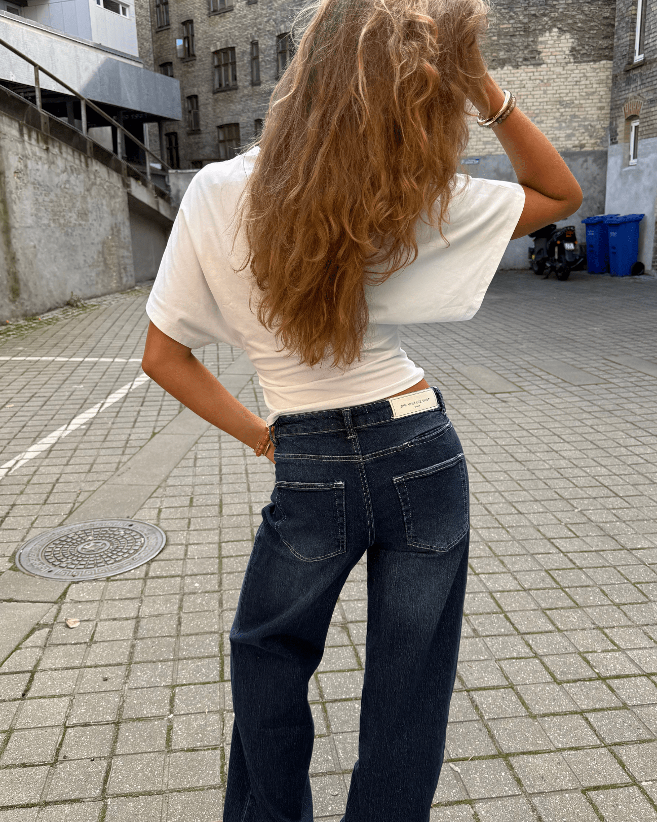 Mørkeblå baggy Alma jeans med mid waist set bagfra på en kvinde i hvid t-shirt.
