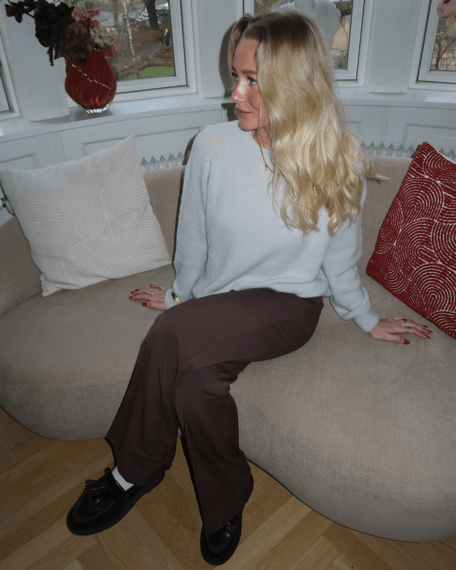 Brun Bella suit pant med straight ben, stylet med en lys striktrøje i en sofa.