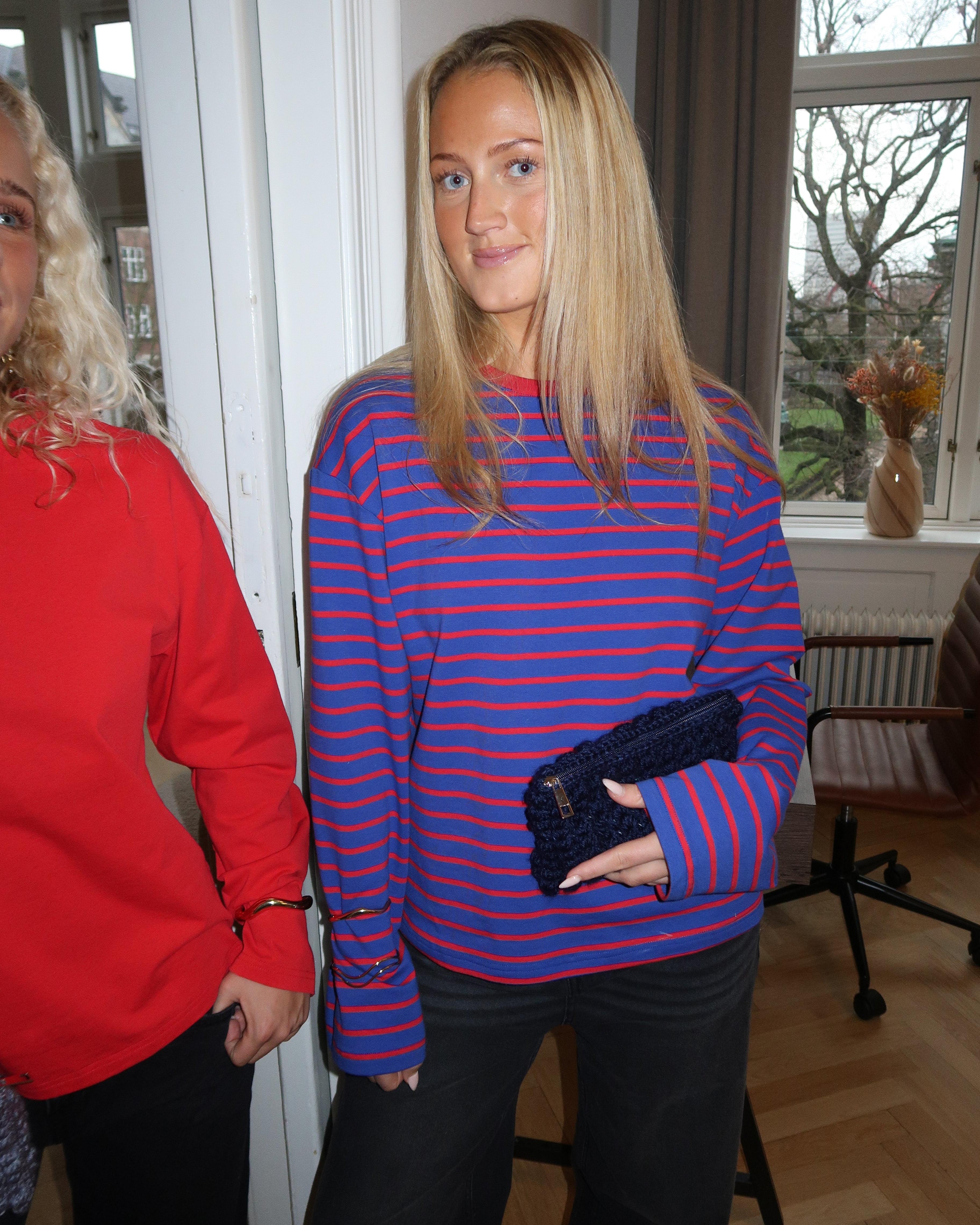 Navyblå hæklet clutch i hånden på kvinde i stribet bluse